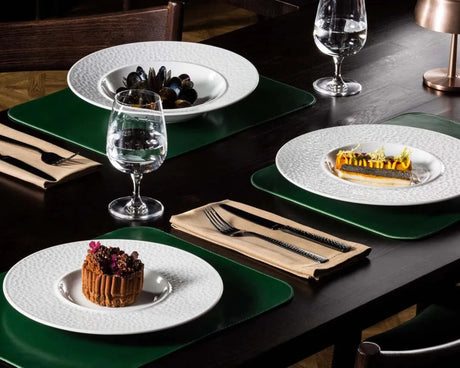 Dining table set with plates, glasses, and desserts on a dark surface.