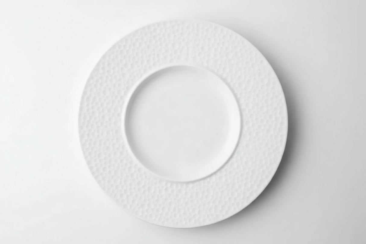 White ceramic plate with textured rim on a white background