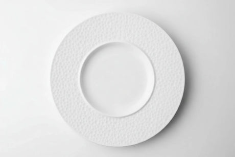 White ceramic plate with textured rim on a white background
